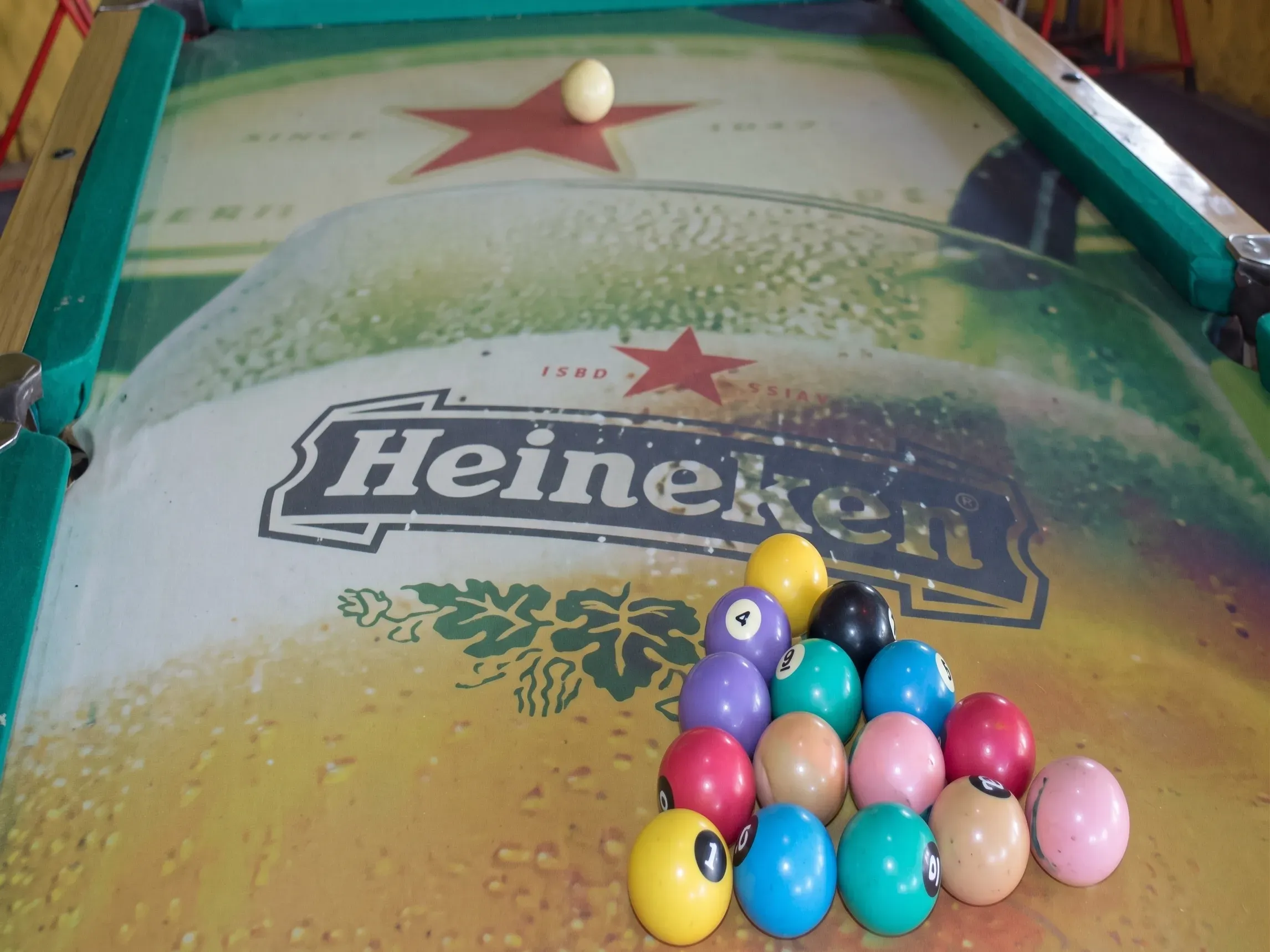 Mesa de bilhar com o feltro de uma marca de cerveja dentro do bar